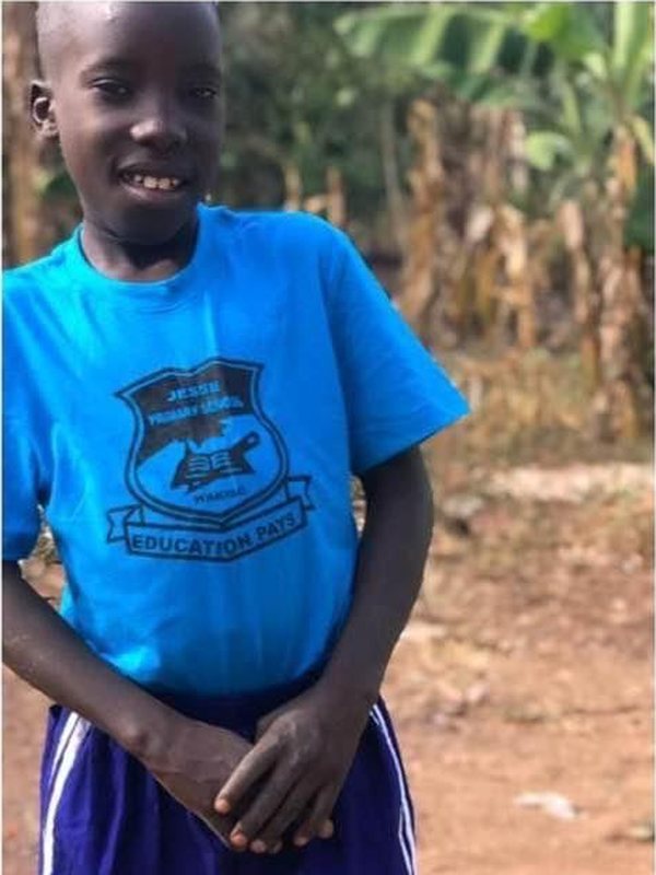 The same boy smiling in a school T-shirt and shorts