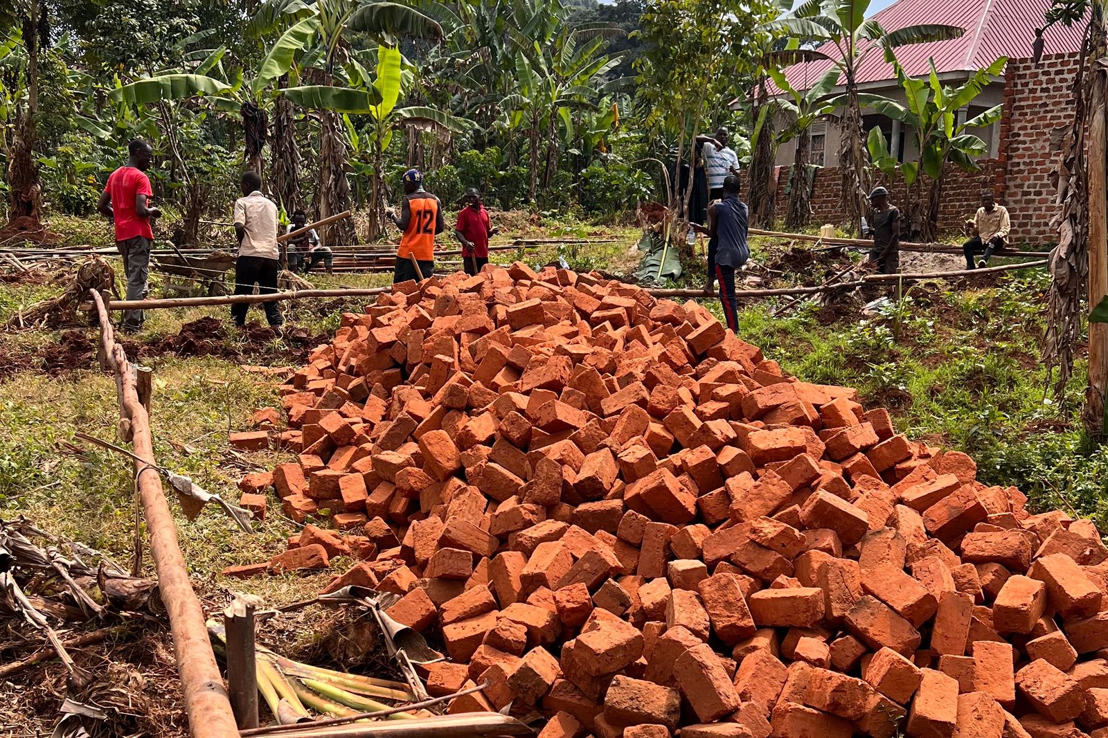 A large pile of red bricks on the school building site, with workers marking out the foundations